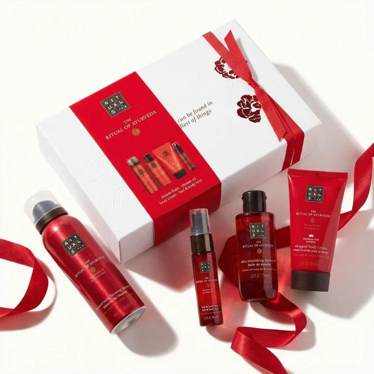 Flat lay: zestaw Rituals The Ritual of Ayurveda – pudełko i kosmetyki na białym tle z czerwoną wstążką.